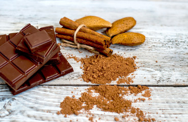 a chocolate bar and cocoa powder with nuts on a light background.