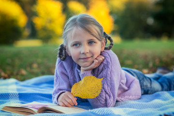 A girl with a book on a plaid in an autumn park © sokko_natalia