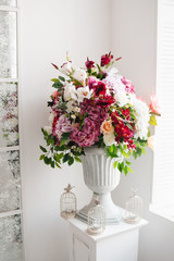 Beautiful flowers in classic white vase. Indoor decoration, gallery. Different colored roses, deep red eustoma, crimson hydrangea in rich blossomed bouquet