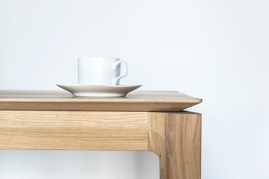 Image of a white porcelain coffee cup on a modern style oak wooden table