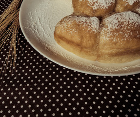 Homemade pastries on a white dish and wheat spikes in vintage processing