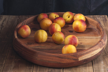 Nectarines lie on a wooden platter