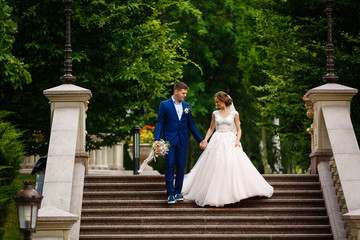 Obraz na płótnie Canvas beautiful groom and the bride on a staircase in the palace