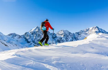 Papier Peint photo Lavable Sports dhiver Ski de randonnée alpiniste marchant le long d& 39 une crête enneigée avec des skis dans le sac à dos. En arrière-plan ciel bleu et soleil brillant et Zebru, Ortler dans le Tyrol du Sud, Italie. Sport extrême d& 39 hiver d& 39 aventure.