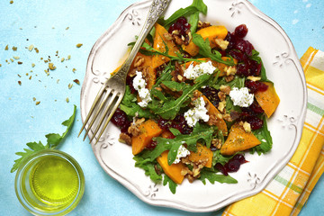 Warm autumn pumpkin salad with dried cranberries,arugula and feta on a vintage plate.Top view.
