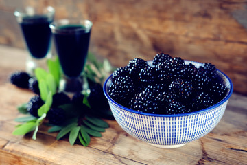 Fototapeta na wymiar Blackberry fruit liqueur in two shot glasses with berries and green leaves
