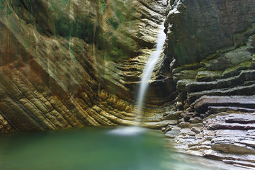 Large deep grotto with a pouring beautiful waterfall © Boris Bulychev