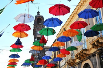Fototapeta na wymiar Aufgehängte Regenschirme über der Wohnstraße als Fest-Dekoration in einer sizilianischen Kleinstadt