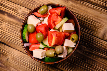 Greek salad in a bowl on wooden table. Top view