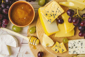 Cheese plate served with honey, fresh grapes and pears