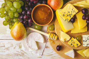 Cheese plate served with honey, fresh grapes and pears