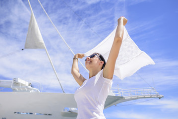 A young woman is holding a wind-scraped scarf in the wind against a white ship's background.
