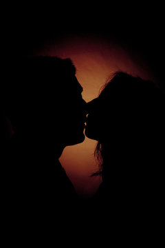 Silhouette Of Two People Kissing On A Dark Background