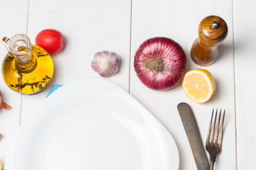 Empty white plate and vegetables around. Copy space.
