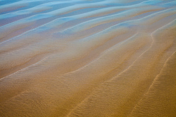 Closeup details of a beach with reflecting blue sky