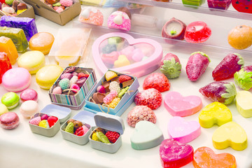 photo handmade soap in the form of sweets, heart, canteen, fruit, in boxes on the table close-up as background under the inscription