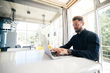 Fototapeta na wymiar Handsome businessman working with laptop in modern bright office