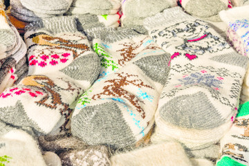 photo on a wooden table lined with piles of winter warm natural woolen socks with different drawings for winter and New Year themes close-up