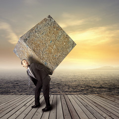 Businessman carrying heavy stone package
