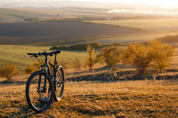 Silhouette of a bike on the hills at sunset.