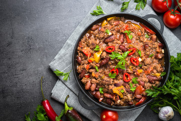 Chili con carne in ijzeren pan op zwarte achtergrond. Traditioneel Mexicaans eten.