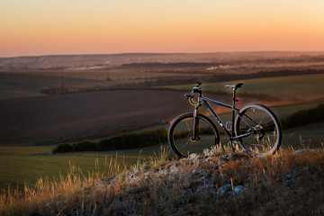 Silhouette of a bike on the hills at sunset.