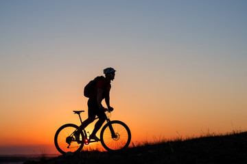 Fototapeta premium Silhouette man stand with mountain bike on the meadow