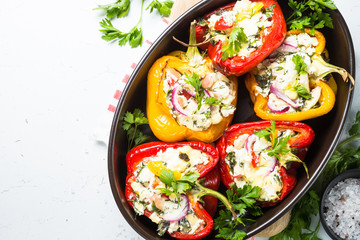 Stuffed paprika peppers with cheese and herbs. Top view on white table.