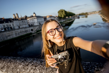 Young woman tourist making selfie photo on the beautiful cityscape background in Orleans, France