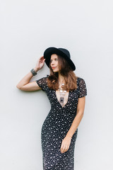 beautiful girl in a black hat and black dress with stars on a white wall background.