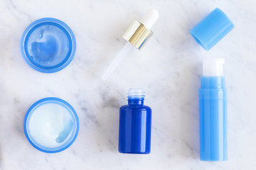 Skincare beauty products on white marble table, top view. Gel cream, serum, moisturizer, lotion. Branding mock up. 