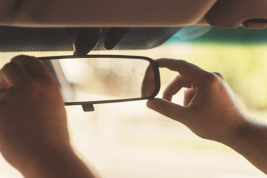 man's hand corrects the rear-view mirror in the car, retro toning