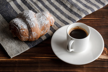Fresh croissants and coffee on wooden table.