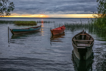three wooden fishing boats on an autumn decline at the coast of the lake