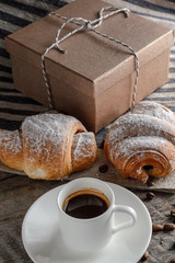 Fresh croissants and coffee on wooden table.