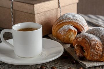 Fresh croissants and coffee on wooden table.