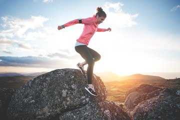 Athletic girl running in the mountains at sunset against the backdrop of a beautiful landscape....