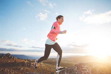 Sports womam running in the mountains at sunset against the backdrop of a beautiful landscape....