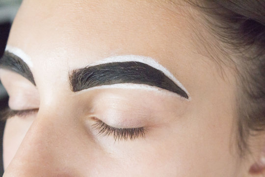 Eyebrow architecture. Eyebrow shaping. Correction makeup and color to the eyebrows with henna in a beauty salon.