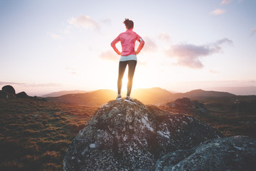 Athletic woman examines mountain landscape for training on running at sunset. Sport tight clothes. 