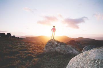 Sports girl examines mountain landscape for training on running at sunset. Sport tight clothes. 