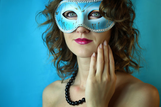 Beautiful young woman in mysterious blue carnival mask. Fashion and beauty photo