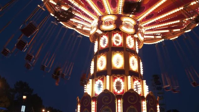 Luminous carousel is spinning in an amusement park at night 4K