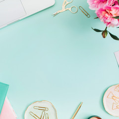 Flat lay home office desk. Female workspace with laptop, pink peonies bouquet, golden accessories, pink and mint diary on mint background. Top view feminine background.