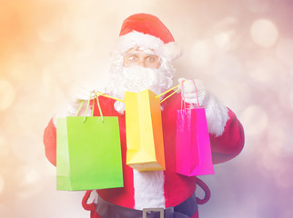 Funny Santa Claus have a fun with shopping bags on blue background