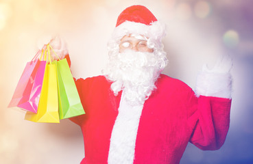 Funny Santa Claus have a fun with shopping bags on blue background