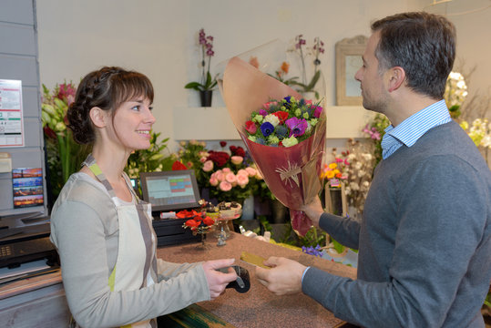 florist and male customer smelling flower bouquet at store