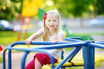 Cute little girl having fun on a playground outdoors in summer.