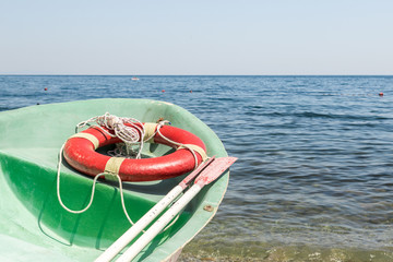 Old green paddle lifeboat on a pebble beach