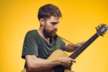 1397945 man holding a guitar on a yellow background, musician